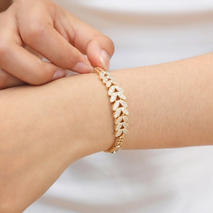 Detail of leaf-shaped gold bracelet with zircon pavé setting on woman's wrist