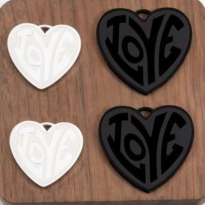 Close-up of heart-shaped LOVE charms in black and white on dark wood background