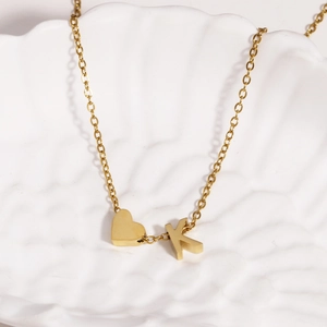 Close-up of 18k gold heart and 'K' letter pendant on a white shell plate