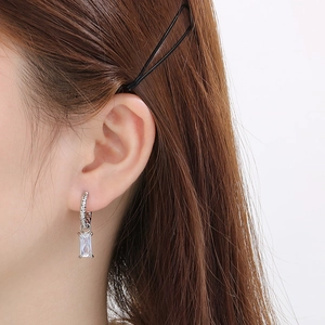 Gros plan de boucles d'oreilles argentées avec zircon rectangulaire sur l'oreille