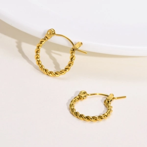 Macro detail of golden twisted rope hoop earrings with a polished metallic finish