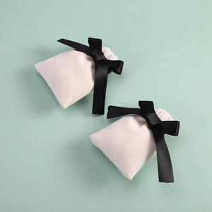 Detailed view of beige velvet jewelry pouch with elegant black satin ribbon bow closure
