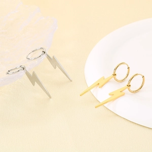 Detailed close-up of gold and silver lightning bolt hoop earrings on a ceramic display
