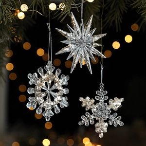 Clear acrylic snowflake and star ornaments with gold sequins hanging on a Christmas tree