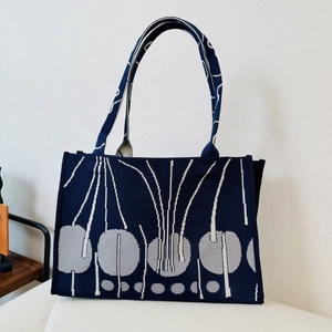 Detailed knit texture of navy tote bag with white lines and grey geometric dot patterns
