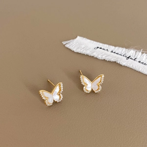 Detailed shot of gold butterfly earrings with white shell inlay and tiny crystals