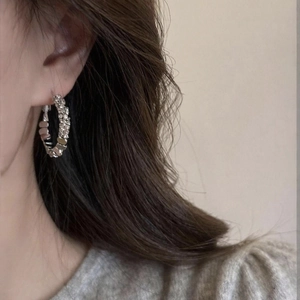 Close-up of sparkling silver geometric hoop earrings with textured finish on a female model