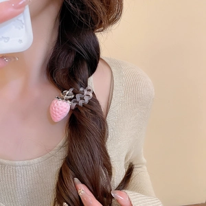 Détail d'un pendentif fraise en peluche sur un élastique à cheveux spirale givré