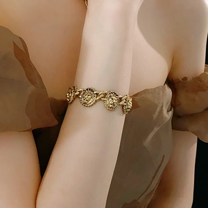 Vue détaillée d'un bracelet vintage doré à maillons tête de lion sur le poignet d'un mannequin