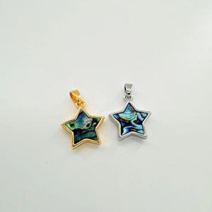 Macro shot of 18K gold and silver star pendants with iridescent natural shell inlay