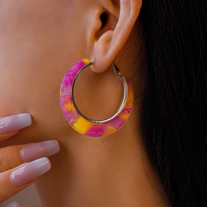 Close-up of model wearing pink and yellow marbled acetate C-shaped hoop earrings