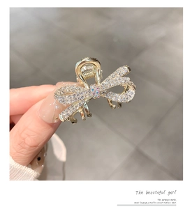 Macro shot of gold bow hair claw with shimmering crystals and rhinestone accents