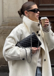 Close-up of a quilted leather chain bag paired with a wool coat and stylish sunglasses