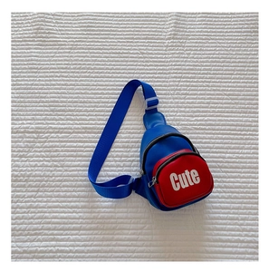 Close-up of blue and red kids crossbody bag with Cute text on quilted surface