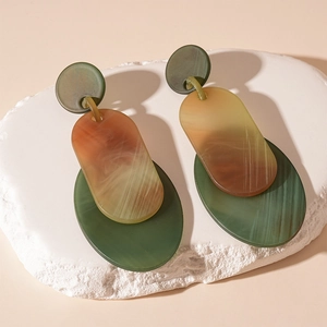 Gros plan de boucles d'oreilles géométriques en acrylique avec texture marbre