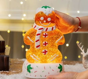 Detailed view of an illuminated gingerbread man snow globe being held in hands