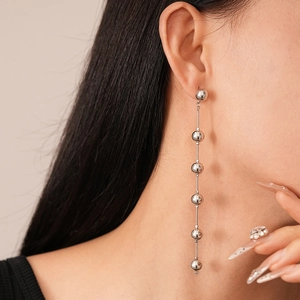 Detail view of silver drop earrings with metallic beads on model with neutral background