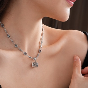 Close-up of silver flower chain necklace with black and red gems on a fashion model