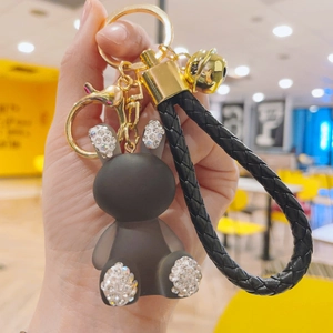 Detail of dark gray matte bunny keychain with rhinestones and golden bell on leather strap