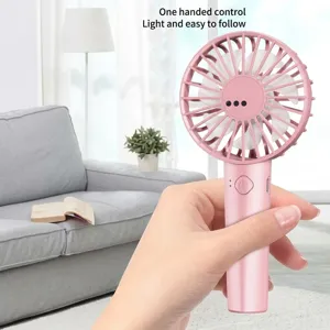 Macro shot of a handheld pink mini USB fan being held by a hand in a home setting