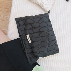 Detailed view of black textured clutch with unique scale pattern and simple wish tag
