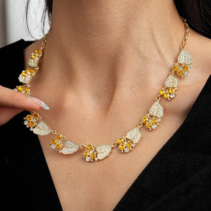 Detailopname van dubbellaagse gouden ketting met bladhangers en fonkelende zirkonia
