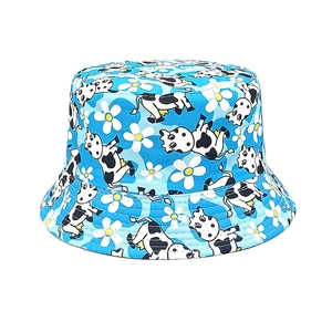 Détail d'un chapeau bob enfant bleu ciel avec motifs de vaches et marguerites