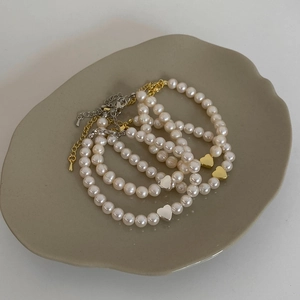 Detail of four natural freshwater pearl bracelets with gold and silver heart pendants