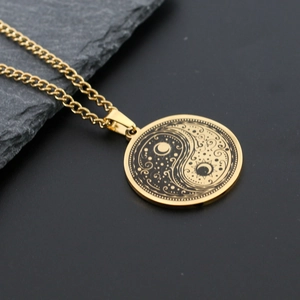 Macro detail of gold Yin Yang Tai Chi necklace pendant resting on a dark rock