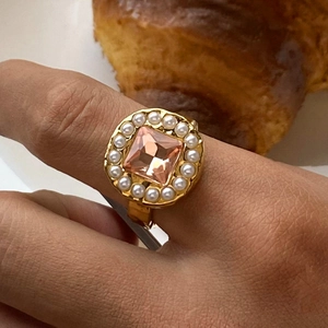 Detailed close-up of a vintage gold ring with a pink square gem and pearl border