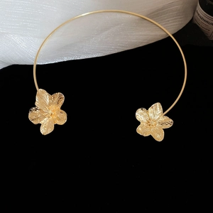Macro detail of gold flower choker featuring intricate textured petals and open collar