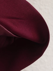 Macro shot of burgundy twill fabric showing detailed material texture and fold