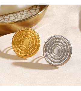 Detail of round wave textured metal rings in gold and silver on an elegant silk fabric