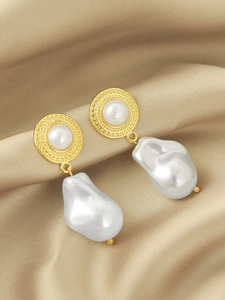 Detailed view of long baroque pearl drop earrings with gold embossed accents on silk