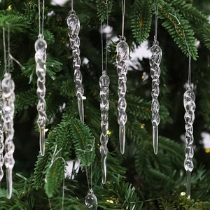 Close-up of clear twisted icicle ornaments hanging on green Christmas tree branches