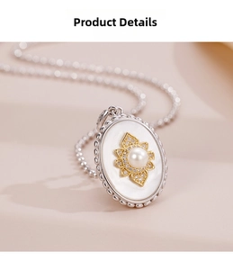 Detail view of oval mother of pearl pendant with gold flower and pearl inlay on silver chain
