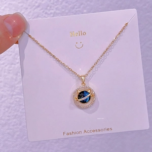 Dettaglio della collana con ciondolo a pianeta dorato con centro galassia blu e cristalli