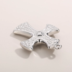 Macro shot of silver stainless steel cross pendant with intricate embossed floral patterns