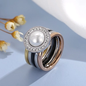 Macro view of stackable rings featuring multi-color bands with a central pearl and zircons