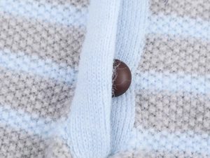 Detail of light blue and grey striped knit vest with a dark brown round button close-up