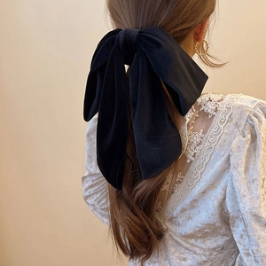 Macro shot of elegant black velvet bow hair tie with long ribbons on a ponytail