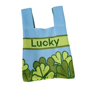 Knitted blue tote bag with green clover patterns and Lucky text on white background