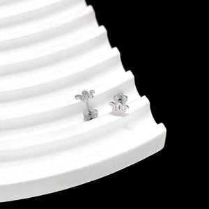 Detailed close-up of silver snake and flower stud earrings on a wavy display stand