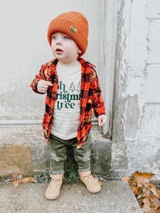 Detail shot of toddler winter outfit featuring an orange knit hat and plaid shirt outdoors