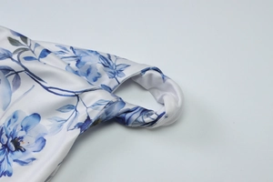 Detail of the twisted shoulder strap and blue floral print on a slim long dress
