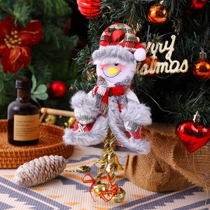 Detailed view of snowman ornament with red plaid fabric and golden bells on a festive tree
