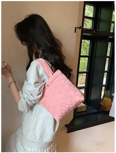 Detail of pink heart quilted tote bag showing a model wearing it as an underarm shoulder bag