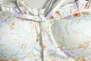 Detailed view of floral print dress featuring ruffled V-neckline and tie-up front design