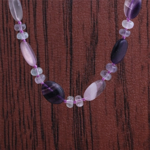 Gros plan de perles d'œil de tigre et de pierre violette sur surface texturée