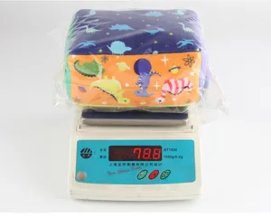 Detailed view of dinosaur plush cube baby toy being weighed on a scale, showing 78.8g weight